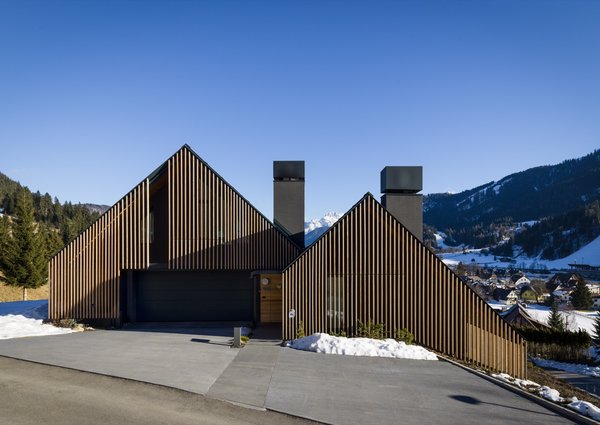 The house is designed to step down the sloped site. Over time, the larch screens will develop a gray patina and create a cool contrast with the warm-toned interior wood.