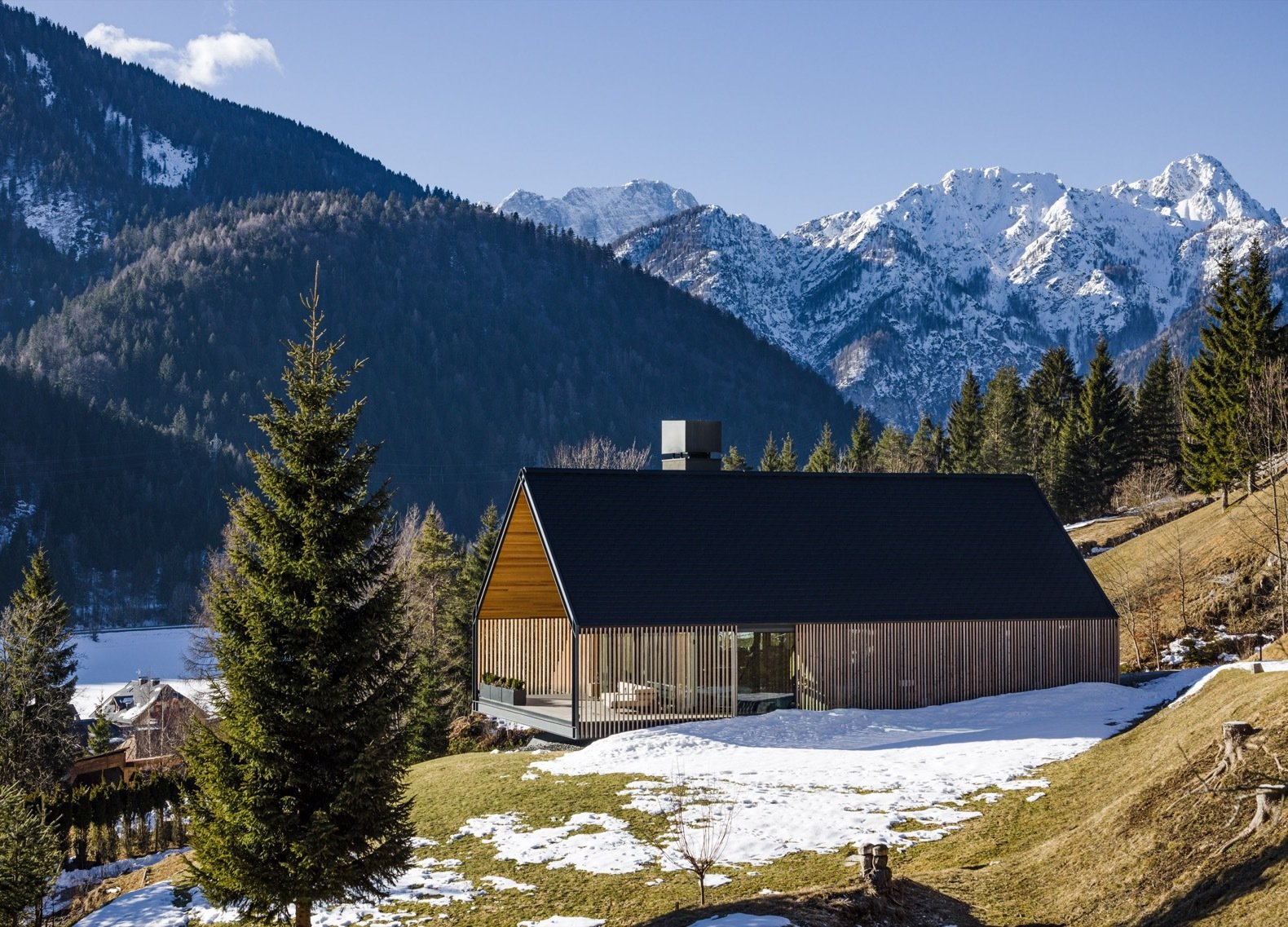 The contemporary home's gabled roofline and timber materials are a nod to the traditional alpine vernacular.
