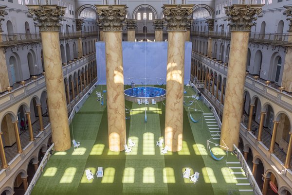 The finished installation features hanging hammocks, a small pool, and a projection of the sky.