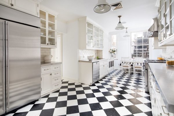 Featuring a timeless black-and-white marble checkerboard floor, the eat-in kitchen receives an abundance of natural light thanks to its huge, six-over-six pane sash window.