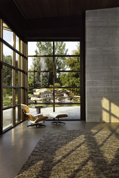 An Eames lounge chair overlooks a cascading waterfall outside the Thompson Lake House. Architect CTA | Cushing Terrell designed the home to feel flexible and customizable.