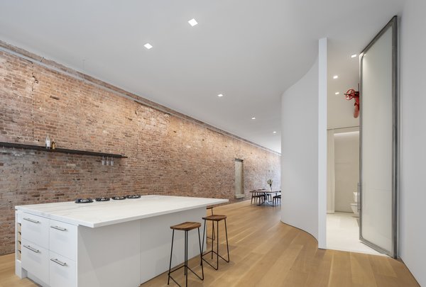 The new layout of the apartment allows for light to stream in from the north and the south. The original brick wall is washed with a continuous, slim LED light. The door to the bathroom is a custom 13-foot-high sandblasted pivot door.