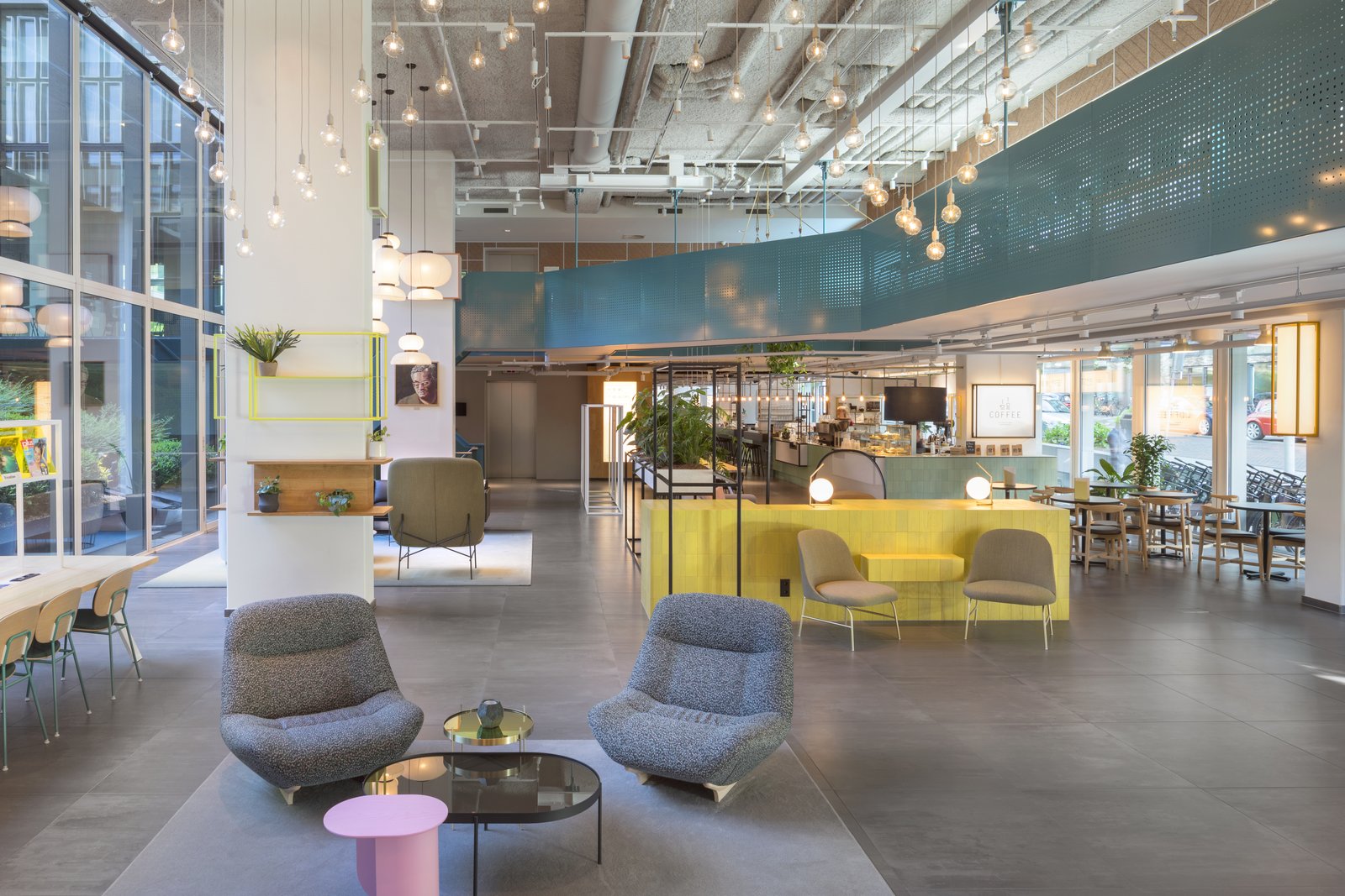 Muuto socket lamps hang from the industrial ceiling of the lobby, where guests choose from a bevy of seating including Ligne Roset armchairs, Viccarbe "Aleta" lounge chairs, and a Tacchini "Kelly H" chair.