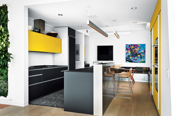 Geraldine and Kit Laybourne remodeled the kitchen in their High Line apartment with yellow and gray interiors. The kitchen features an Artematica Vitrum glass system from Valcucine, artwork by Craig Kucia, and banquette cushion fabrics by Hella Jongerius for Maharam.