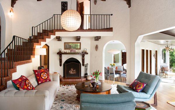 Bright, airy, and spacious, the two-story living room is steeped in historic charm, featuring the home's original wooden mantel, beamed ceilings, and open brick staircase.