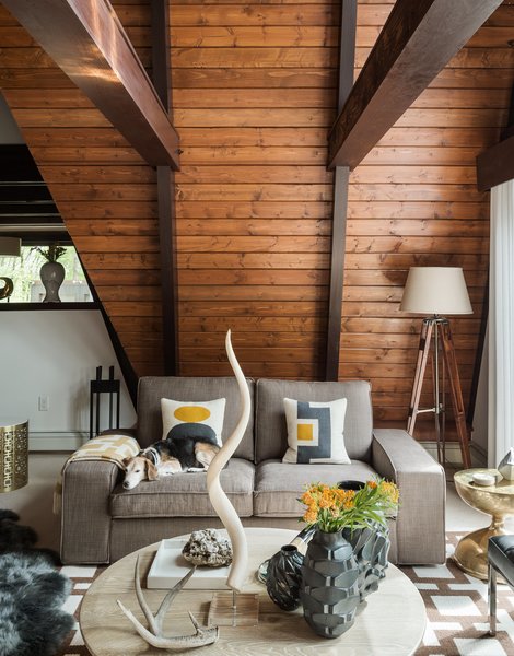 Original tongue-and-groove pine boards, restained a warm chestnut hue, run horizontally to the ceiling. The residents layered gray sheepskin rugs on top of wool berber carpeting, installed by Joseph Velletri’s Sons.