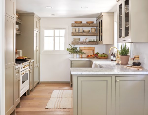 The new layout feels more open and spacious, thanks in part to strategic open shelving and chicken wire on the cabinet fronts. All of the bowls and boards are by Elsie Green, and the ceramics are from Jenni Kayne. 