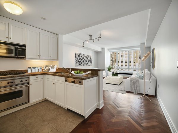 One inside , a luxury kitchen is located to the left, with a peninsula flowing into the living room. The apartment is virtually staged to provide ideas for furniture placement.