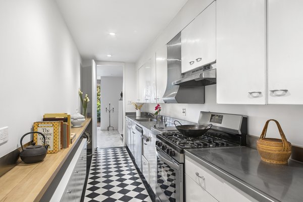 A galley kitchen—equipped with stainless-steel appliances and countertops—is located on the garden floor and accessed from the main foyer. Steps away is a large pantry that includes additional cabinetry, as well as another sink. 