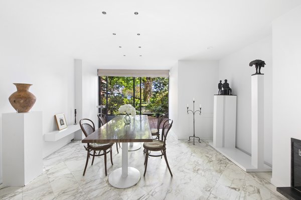 Marble lines the floor of the home's formal dining area, while oversized glass doors frame views out to the garden. The space is large enough to accommodate easy entertaining.
