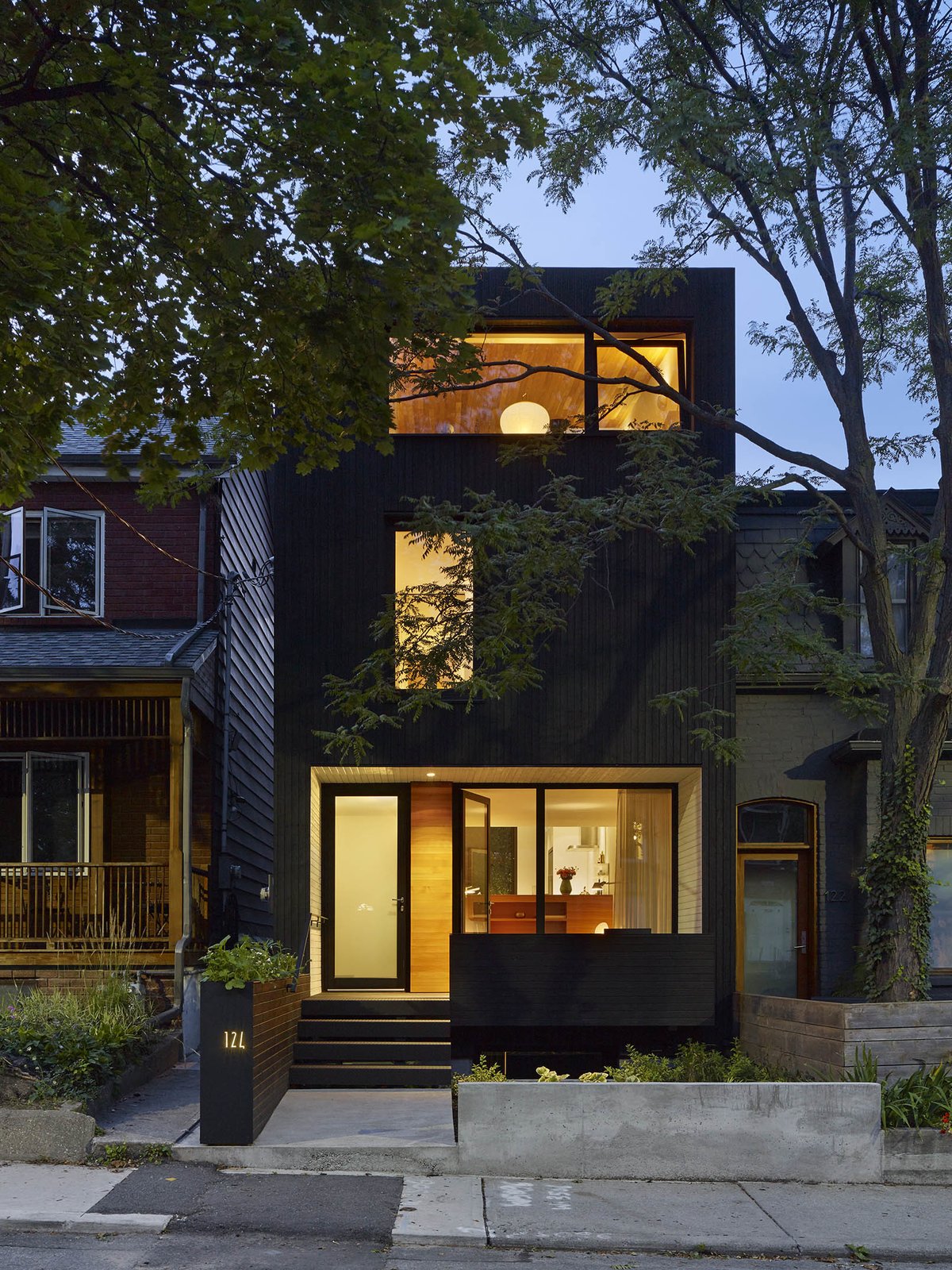 The all-black exterior cladding creates a quiet pause in the streetscape. By day, it acts as an abstract canvas for shadow play from the boulevard trees. By night, it has the quality of an austere lantern.