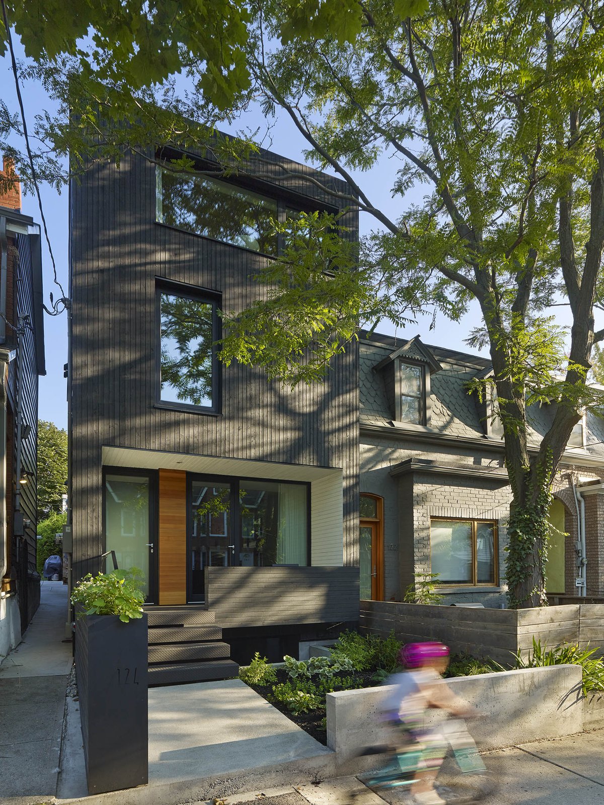 The all-black exterior cladding creates a quiet pause in the streetscape. By day, it acts as an abstract canvas for shadow play from the boulevard trees. By night, it has the quality of an austere lantern.
