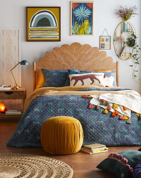 A Bohemian Carved Wood Headboard pairs with the Jungle Leopard Quilt Set and a Rainbow Pom Decorative Throw.