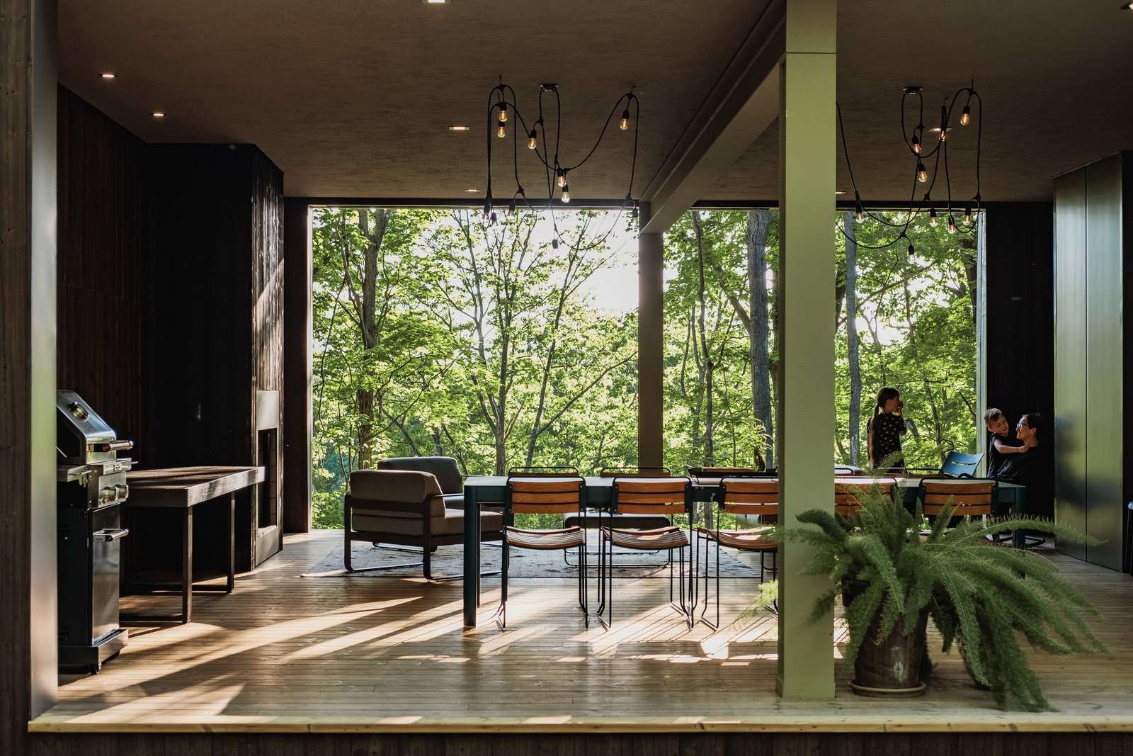 In addition to its sloping, tree-covered lot, what makes the Birch Le Collaboration House so special is the home's large, indoor-outdoor covered porch. The space is an extension of the floor-to-ceiling windows that line the walls of every Hygge Supply home. The Birch Le Collaboration House is also the first Hygge Supply home to be finished in black-stained Thermory pine cladding.