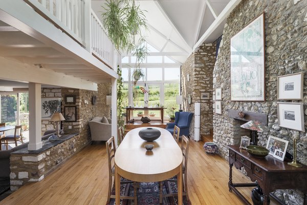 The full-height chimney stack creates a natural division between the dining and living room to the right. A wall of windows caps one end of the space, warming it with natural light and providing picturesque views of the landscape.