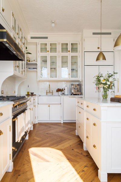 In this exquisite, classically styled black and white kitchen, gleaming white marble countertops and cabinets are juxtaposed by a dramatic, gold-trimmed black oven and range hood. Two Bestlite Pendants from Gobi enhance the gold details throughout this kitchen, a favorite among black and white kitchens. 