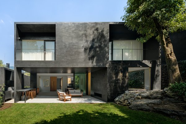 The home embraces its green surroundings with outdoor terraces, open living spaces, and large windows. 