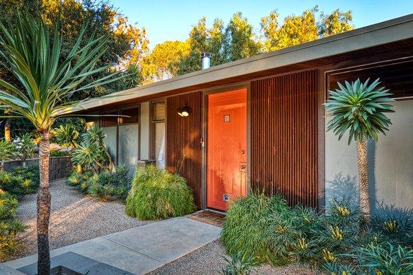 The Aurora Orange front door makes a classic midcentury statement. Clad in vertically laid wooden slats, the exterior previews details found throughout the interior.