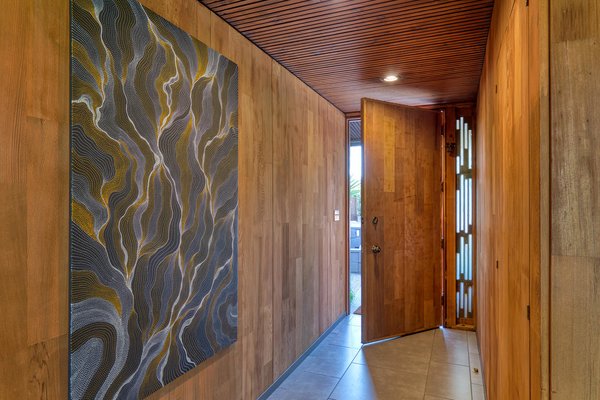 The front door opens to reveal redwood paneling and a slatted ceiling. The property was once part of a compound designed for the architect’s family.