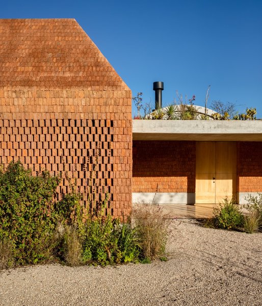 On a plateau three hours outside Mexico City, architect Fernanda Canales created a wild, nature-fueled vacation home for her family surrounding four courtyards. Celebrating the flat, rugged environs, she melded a facade of red, broken brick with warm concrete and wood interiors. To add extra height, she turned to terra-cotta tiled barrel vaults.