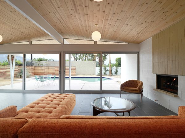 Wall-to-wall sliding glass doors open the living room to the backyard patio, while also framing views of the pool. Globe pendant lights enhance the home's vintage flair.