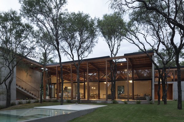 The large social space at the center of the home opens out to views of the surrounding trees and the pool.