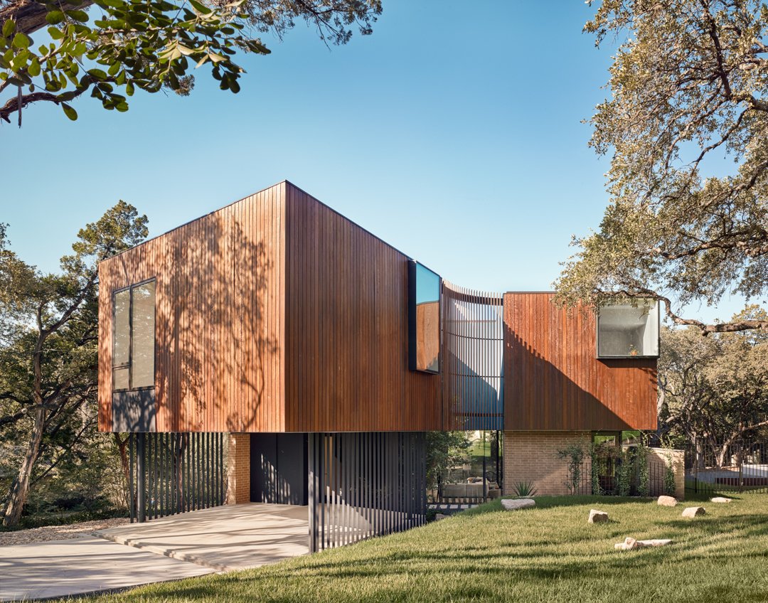 One of the Alterstudio's latest projects relies heavily on strong geometric elements. The entire structure reads as a single box stretched apart in the middle like two sides of an accordion. Vertical slats span between the two sections and enclose a carport underneath a cantilevering upper level.