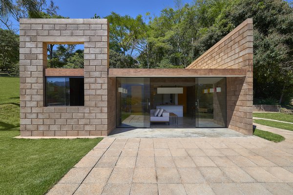 The home’s exterior is composed of stacked blocks made from mining waste and concrete. A glass wall on the rear facade contrasts with the blocks and facilitates an indoor/outdoor connection. 