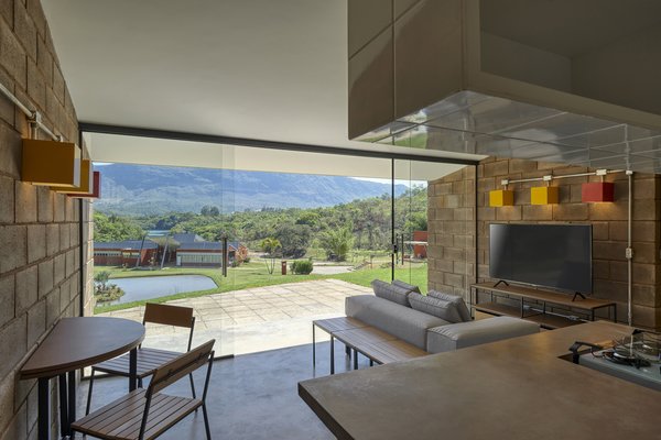 A glass wall on the rear facade ties the compact home to the lush landscape and frames views of mountains, trees, and a lake.