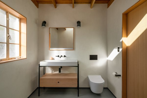The bathroom of a Tucson territorial-style midcentury features tadelakt walls done by a talented local craftsman and Neolith floors. The tub, from Blu Bathworks, sits on a Douglas fir base, so as to look as though it’s floating. Douglas fir wood was used to match the original wood in the home. "Similar to the rest of the home, we wanted to keep the space minimal and austere in design, yet highly functional," says architect Darci Hazelbaker. "With the additional square footage gained from the closets, our intention was to allow that additional space to stay ‘empty.’"