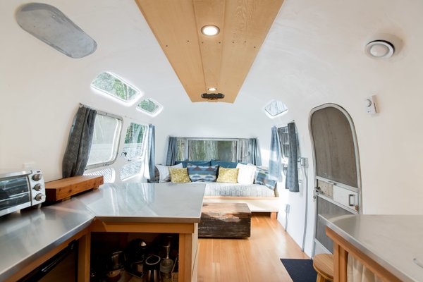 The interior of the Airstream was reimagined using reclaimed materials. The flooring is made of old-growth Douglas fir, and the ceiling features yellow cedar sawmill offcuts. Ryan crafted the built-in sofa using more cedar sawmill offcuts, while Catherine sewed the drapery and the upholstery, using fabric she collected from various thrift shops and IKEA.