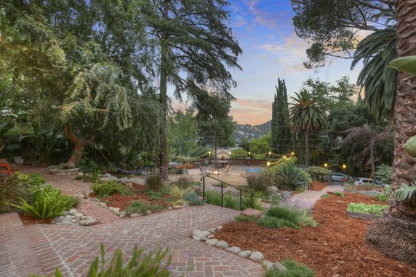 A series of stairs ascend from the street to the main entrance, connecting to a spacious front garden and terrace as well. Views from the top extend across the Arroyo Seco and toward Ernest E. Debs Park in Montecito Heights.