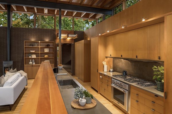 The open kitchen features a long island, dividing it from the living area. The room is supported by steel beams and four steel posts partially encased in wood—all of which are left exposed as a nod to the firm's philosophy of celebrating an honesty with materials.