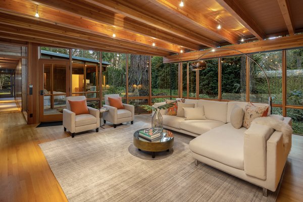 A smaller family room sits on one side of the great room. As in much of the 5,565-square-foot interior, floor-to-ceiling windows provide views of the lush greenery surrounding the home.
