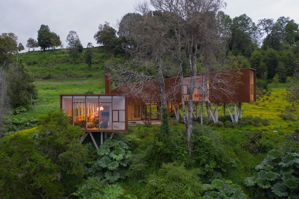 A robust Cor-Ten steel home rises from the rugged landscape.