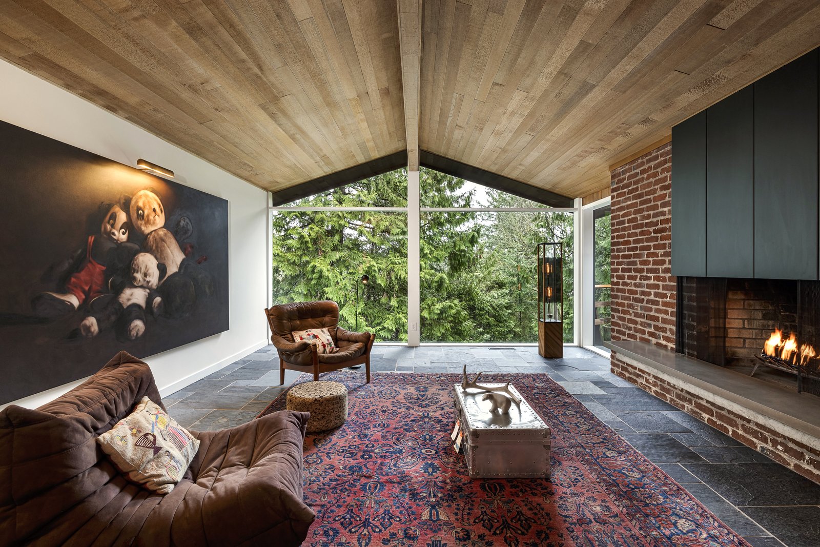 The living room has floor-to-ceiling glass, as well as a custom hood at the fireplace.