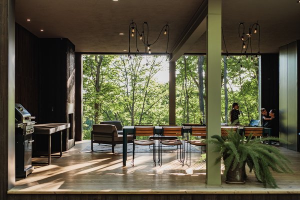 The outdoor living space of the Birch Le Collaboration House features a wood-burning fireplace under large, covered porch.
