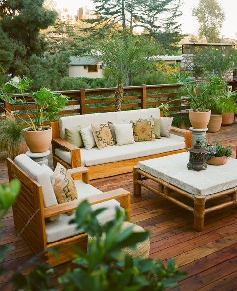 A Mission-style sofa and matching club chair are paired with a bamboo-and-stone table on a secondary outdoor deck, where grilling with friends is a popular pastime.