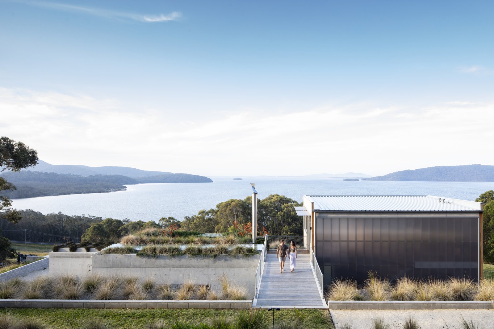 Approaching the home from above, guests encounter a green roof that feels united with the landscape beyond. The entry sequence presents purposefully framed views that hide and reveal the lake.