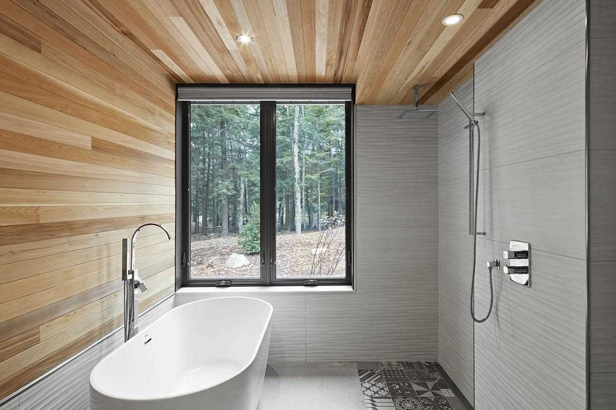A modern bathroom with wood wall and ceiling, and a freestanding bathtub.