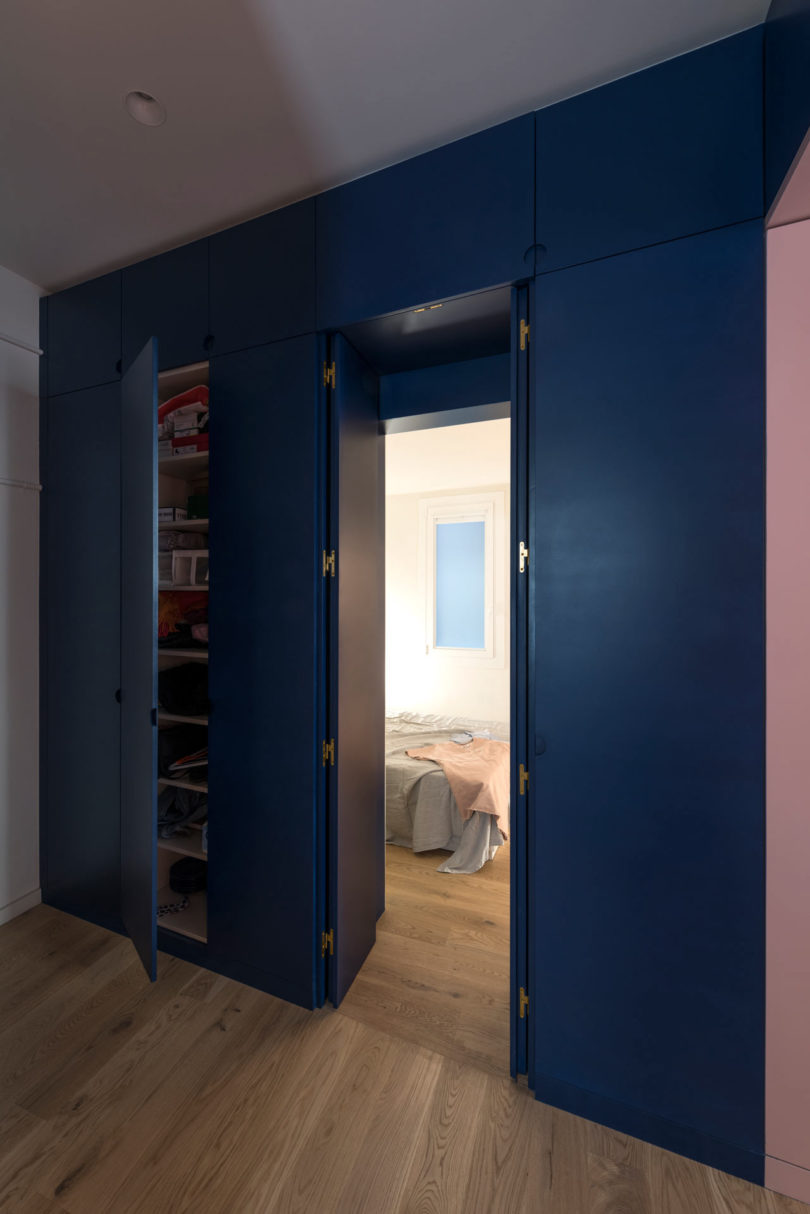navy wall with hidden storage cabinets and passageway into bedroom