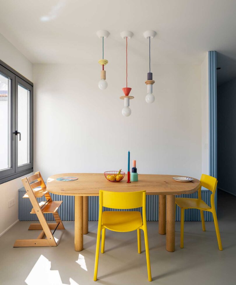 interior view of modern dining room with colorful pendant lights, wood table, and yellow chairs