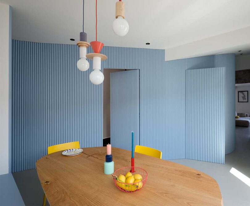 interior view of modern dining room with colorful pendant lights, wood table, and yellow chairs