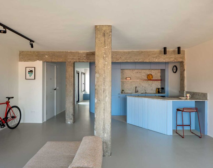 overall interior view of modern industrial apartment with light blue kitchen, minimalist living room, and concrete details