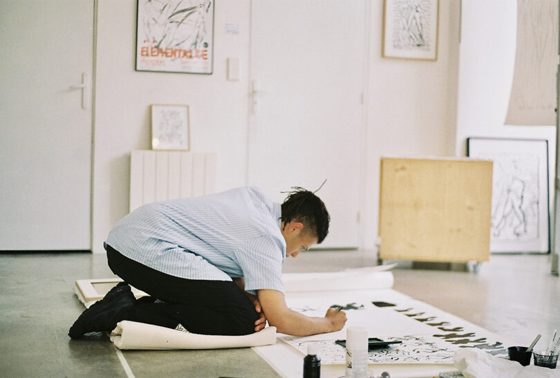 a man drawing on paper on the floor
