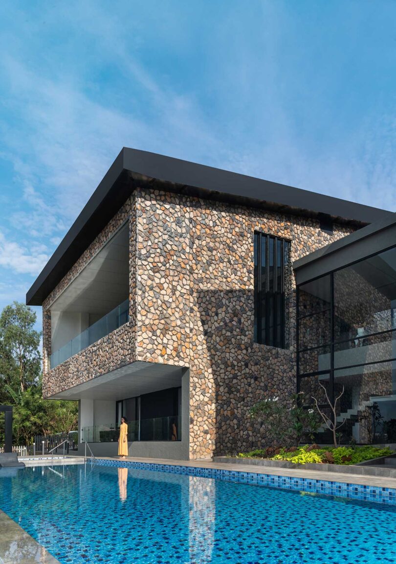 angled partial exterior view of modern stone house with swimming pool