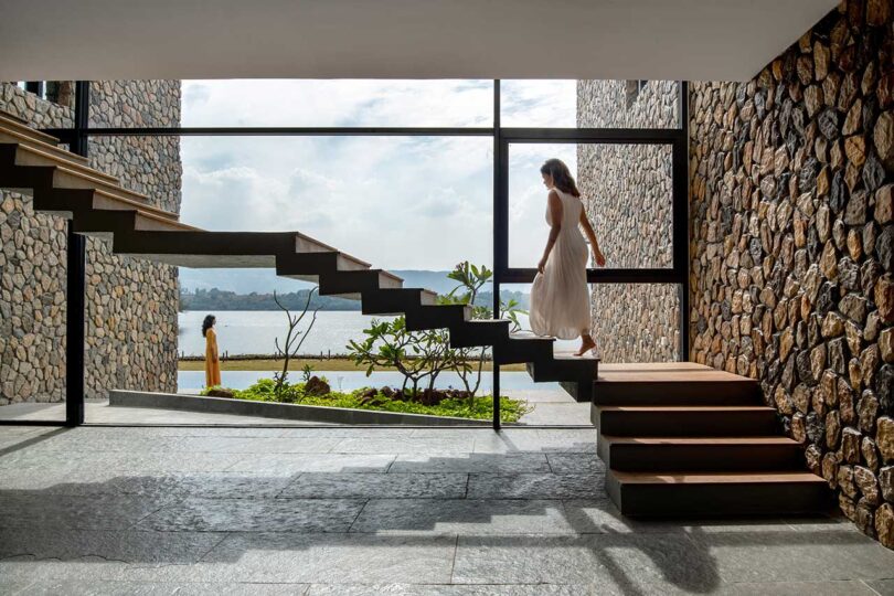 view of minimalist modern floating staircase in front of window with woman walking up