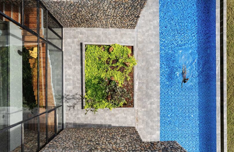 aerial view looking down at modern stone house with elongated swimming pool