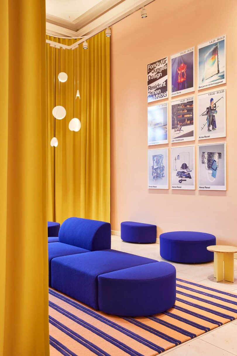 interior view of modern museum seating area of modular cobalt seating, pink walls, and yellow curtains