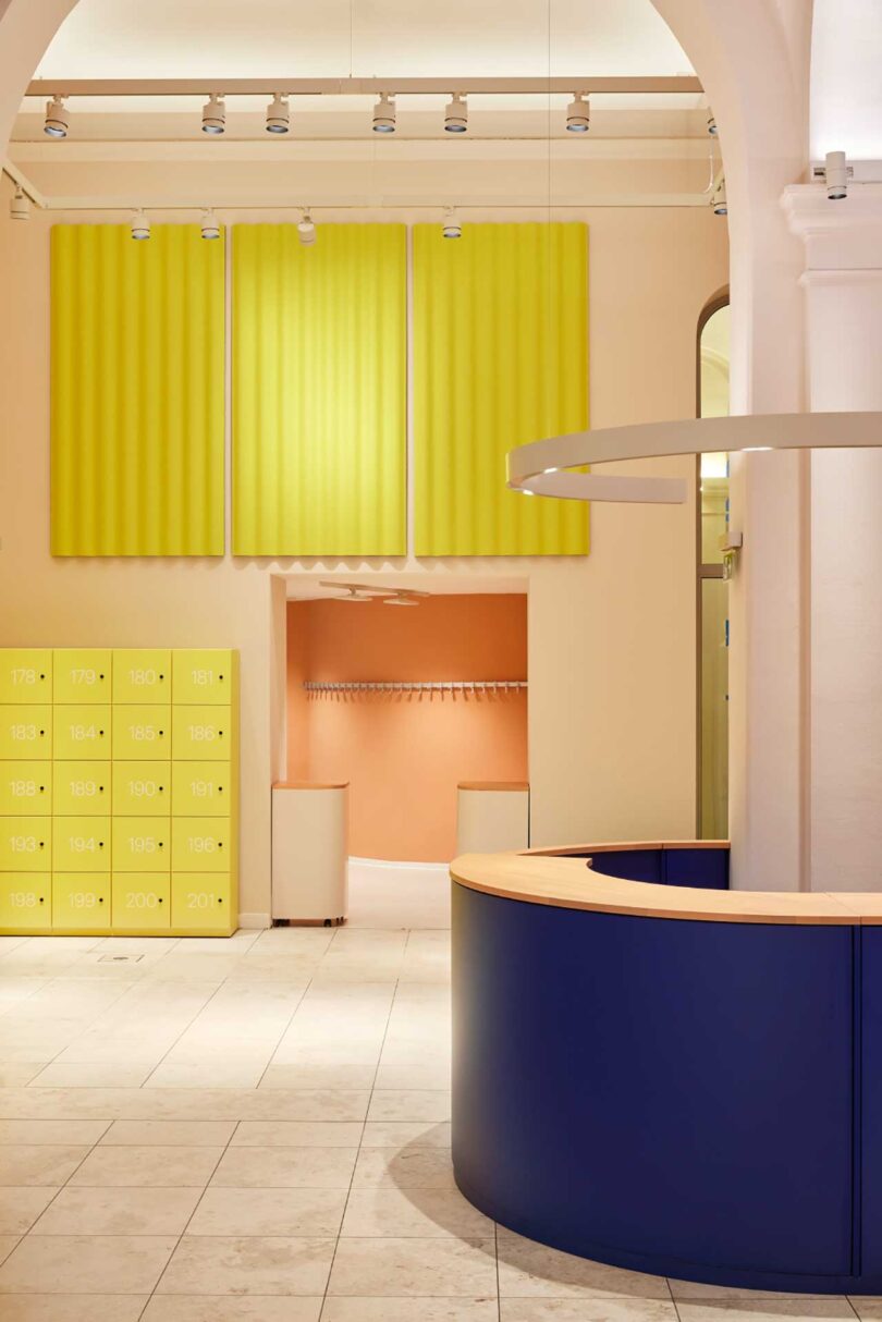 modern museum interior with blue kiosk and bright yellow lockers